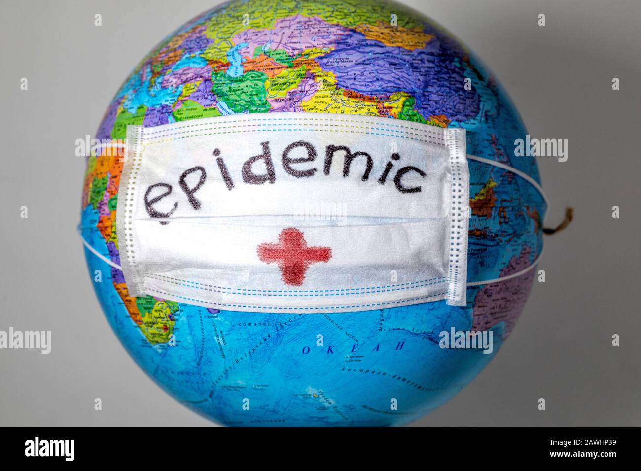 Globe with a political map of the world with a white medical mask and the inscription `Epidemic` Stock Photo